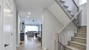 Un interior moderno con una escalera, piso de madera y un comedor con vista al exterior.