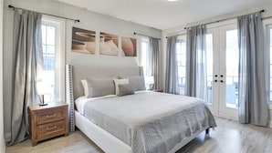 Un dormitorio con cama, mesita de noche y cortinas.