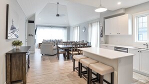 Una cocina moderna con una isla central, suelo de madera y armarios blancos.