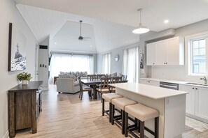 A modern kitchen with a central island, wooden flooring, and white cabinetry.