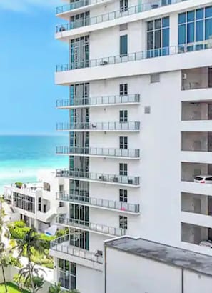 Un hotel de varios pisos con balcones, ventanas grandes y vista a la playa.