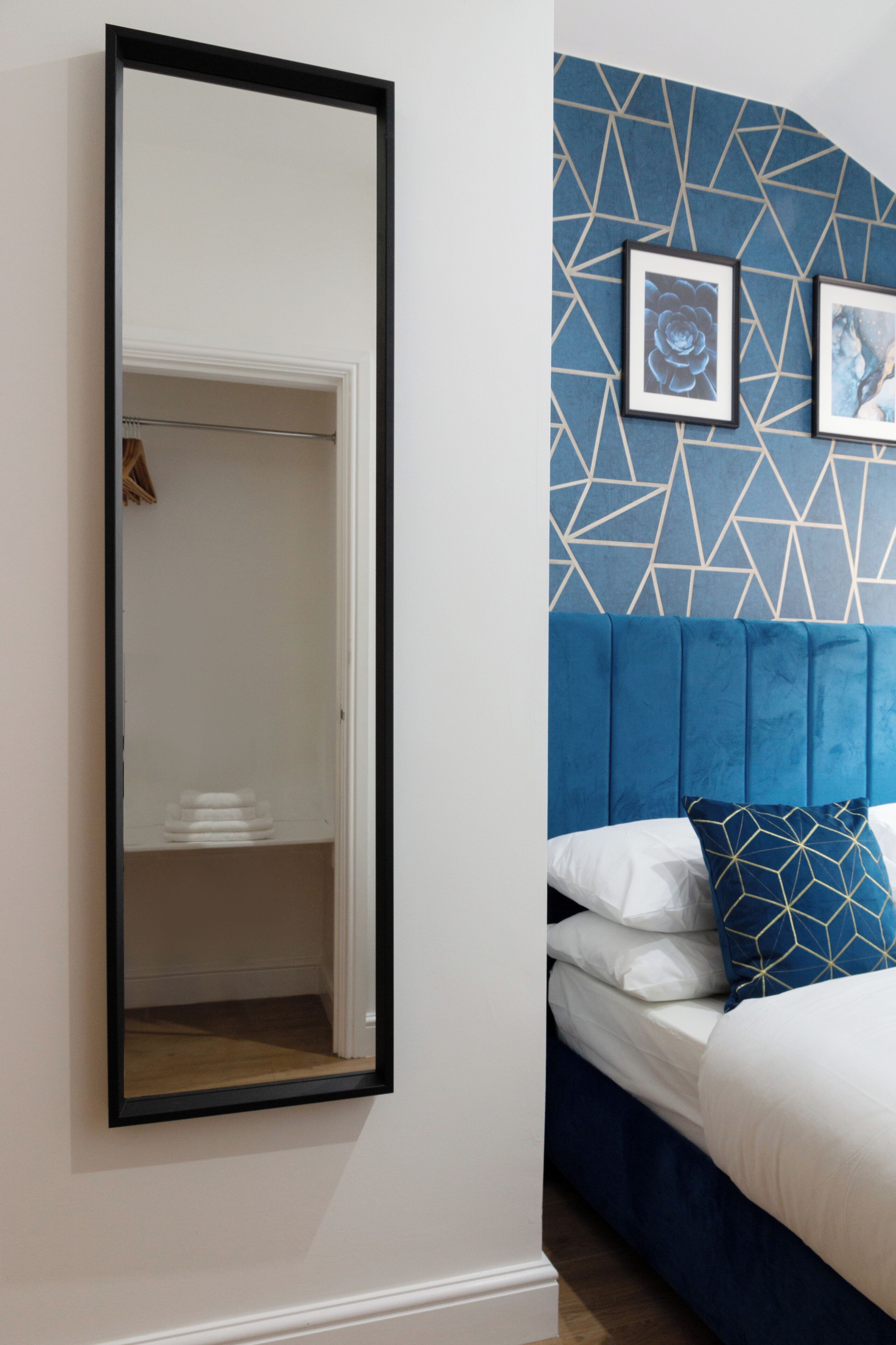 A bedroom with a bed, a mirror, and a wardrobe.