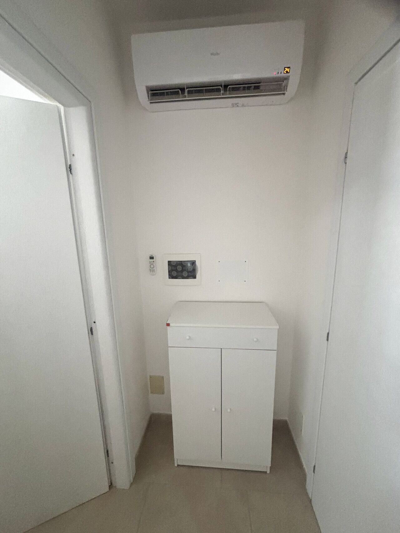 Pequeña lavandería cerrada con lavadora blanca, calentador en la pared y una puerta.