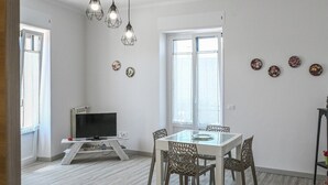 Un salon moderne avec un téléviseur, une table à manger, des chaises et des assiettes décoratives accrochées au mur.