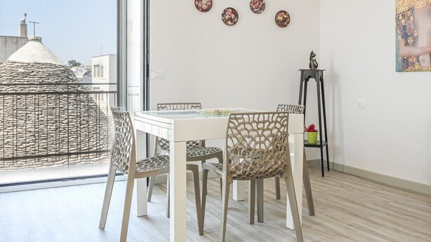 Un balcon avec une table et des chaises, une vue sur les immeubles et un tableau accroché au mur.