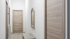 Un couloir avec des portes en bois, un radiateur et une petite table.