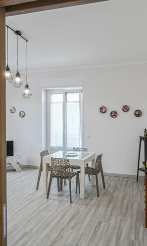 A dining area with a glass table, chairs, and hanging lights.