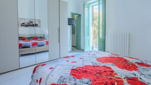 A bedroom with a bed, a wardrobe, a radiator, and a door leading to another room.