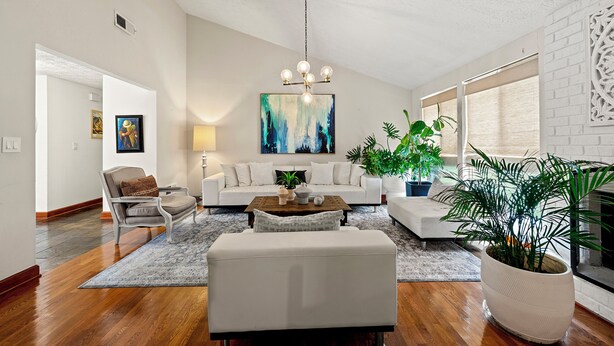 Un salon spacieux avec un canapé blanc, un fauteuil blanc, une table basse et une grande plante en pot.