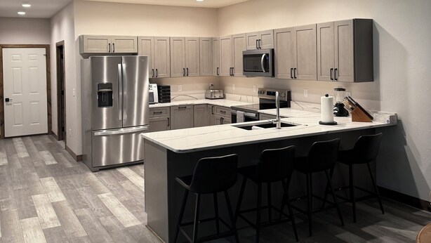 Una cocina moderna con una isla central, electrodomésticos de acero inoxidable y taburetes de bar.
