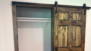 Una habitación con una puerta corredera de madera y un armario blanco con una barra metálica.