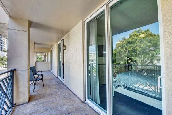 A balcony with a glass door, a chair, and a view of trees and buildings.