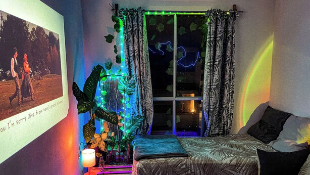 A bedroom with a bed, a window with curtains, a wall with a picture, and a neon light decoration.