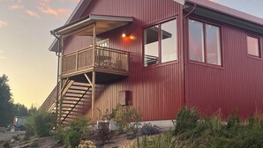 A two-story building with a balcony and a staircase leading to the upper floor. - Farm idyll with lake views, private beach spot & boat near the west coast (Västra Götalands län)