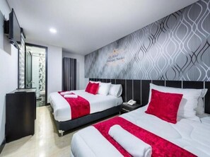 Une chambre d’hôtel avec deux lits, un bureau, un miroir et un mur décoré de motifs.