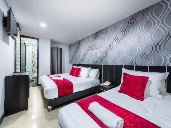 A hotel room with two beds, a TV, and a bathroom visible through a glass door. - CASA HOTEL BOUTIQUE MARKES (Bogotá)