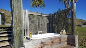 A wooden deck with a hot tub, surrounded by a wooden fence and a bamboo wall. - Hurunui River Retreat - Tussock Cottage (Canterbury)