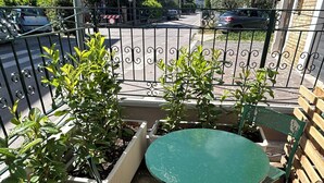 A balcony with a round table and chairs, surrounded by potted plants.