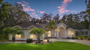 A two-story house with a well-maintained lawn, a covered patio, and a large window overlooking the property. - Charming Golf Retreat - Pool/hot tub sleep 6 (Inverness)