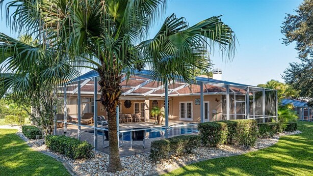A house with a pool, covered patio, and palm trees. - Charming Golf Retreat - Pool/hot tub sleep 6 (Inverness)
