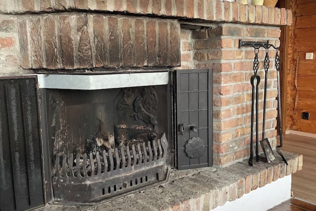 A fireplace with a metal grate, a decorative panel, and a door with a handle.