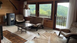 A cozy room with a wooden interior, a sofa, a coffee table, and a television. - Urlaubsstube1982 - wildly romantic with a fireplace and rustic charm (Schöfweg)