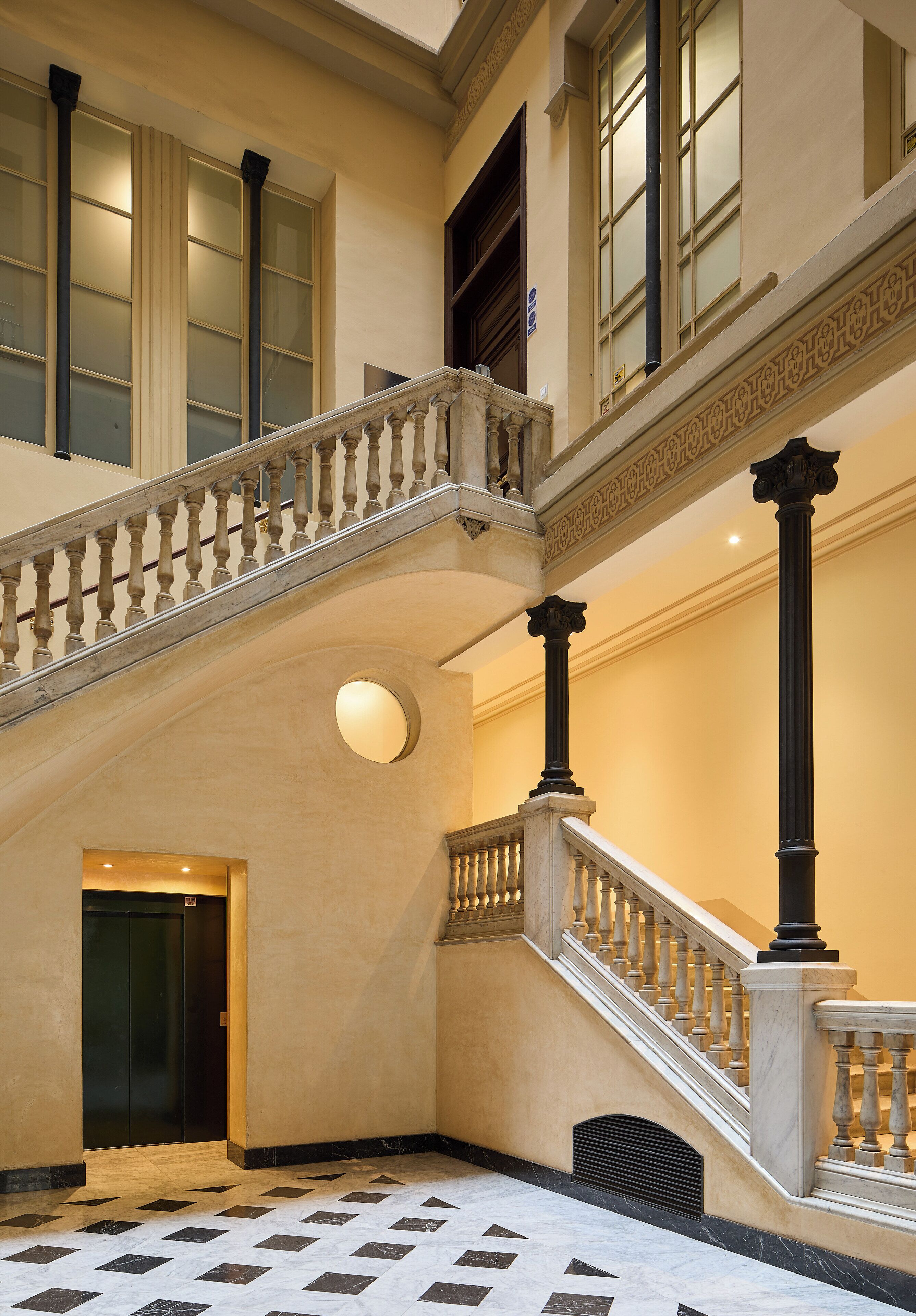 Eine prächtige Treppe mit Geländer, einem runden Ziertelement und einer Tür am Fuß.
