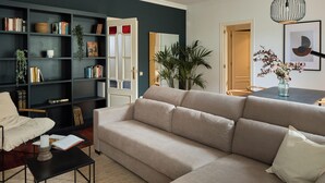 A living room with a beige sofa, a bookshelf, and a dining area with a table and chairs. - Stay U-nique Apartments Ronda Sant Pere (Barcelona)