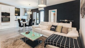 A modern living room with a sofa, coffee table, and a dining area with chairs and a table. - Stay U-nique Apartments Aprestadora (L'Hospitalet de Llobregat)