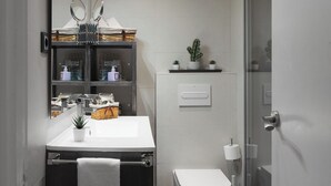 A modern bathroom with a white sink, mirror, and toilet. There are plants on the shelf and a towel hanging on the towel rack. - Stay U-nique Apartments Aprestadora (L'Hospitalet de Llobregat)
