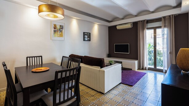 Un salon moderne comprenant un coin repas, un canapé, un téléviseur et une fenêtre avec des rideaux.