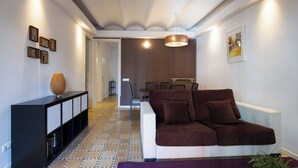 Un salon moderne avec un canapé marron, une console noire et un sol à motifs.