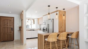 A modern kitchen with a wooden island, bar stools, and pendant lighting. - Stay U-nique Villa Mar Baltico (Benalmádena)