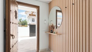 A hallway with a wooden door, a mirror, and a shelf with decorative items. - Stay U-nique Villa Mar Baltico (Benalmádena)