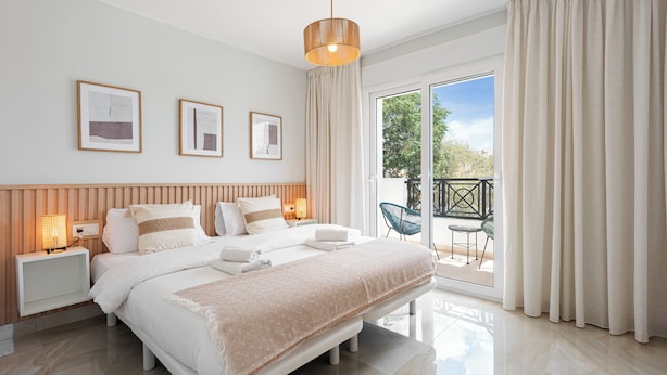 A modern bedroom with a large bed, bedside tables, and a view of the outdoors. - Stay U-nique Villa Mar Baltico (Benalmádena)