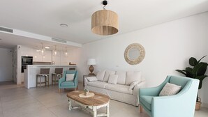A modern living room with a sofa, two armchairs, a coffee table, and a kitchen area in the background. - Stay U-nique Apartment Romana (Marbella)