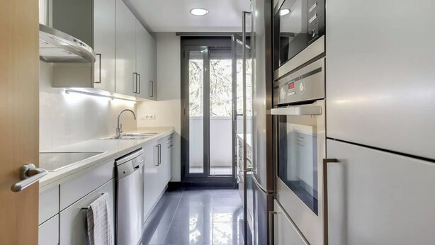 A modern kitchen with stainless steel appliances, a dishwasher, and a large window providing natural light. - Stay U-nique Apartments Diagonal Mar (Barcelona)