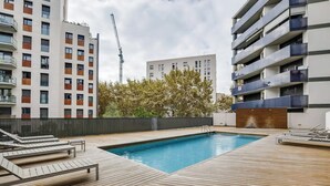 A modern apartment complex with a rooftop pool area, including wooden decking and lounge chairs. - Stay U-nique Apartments Diagonal Mar (Barcelona)