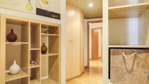 A room with a wooden wardrobe, a shelf with decorative vases, and a framed picture on the wall. - Stay U-nique Apartments Diagonal Mar (Barcelona)