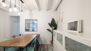 A dining area with a wooden table and teal chairs, white walls, and a large plant.