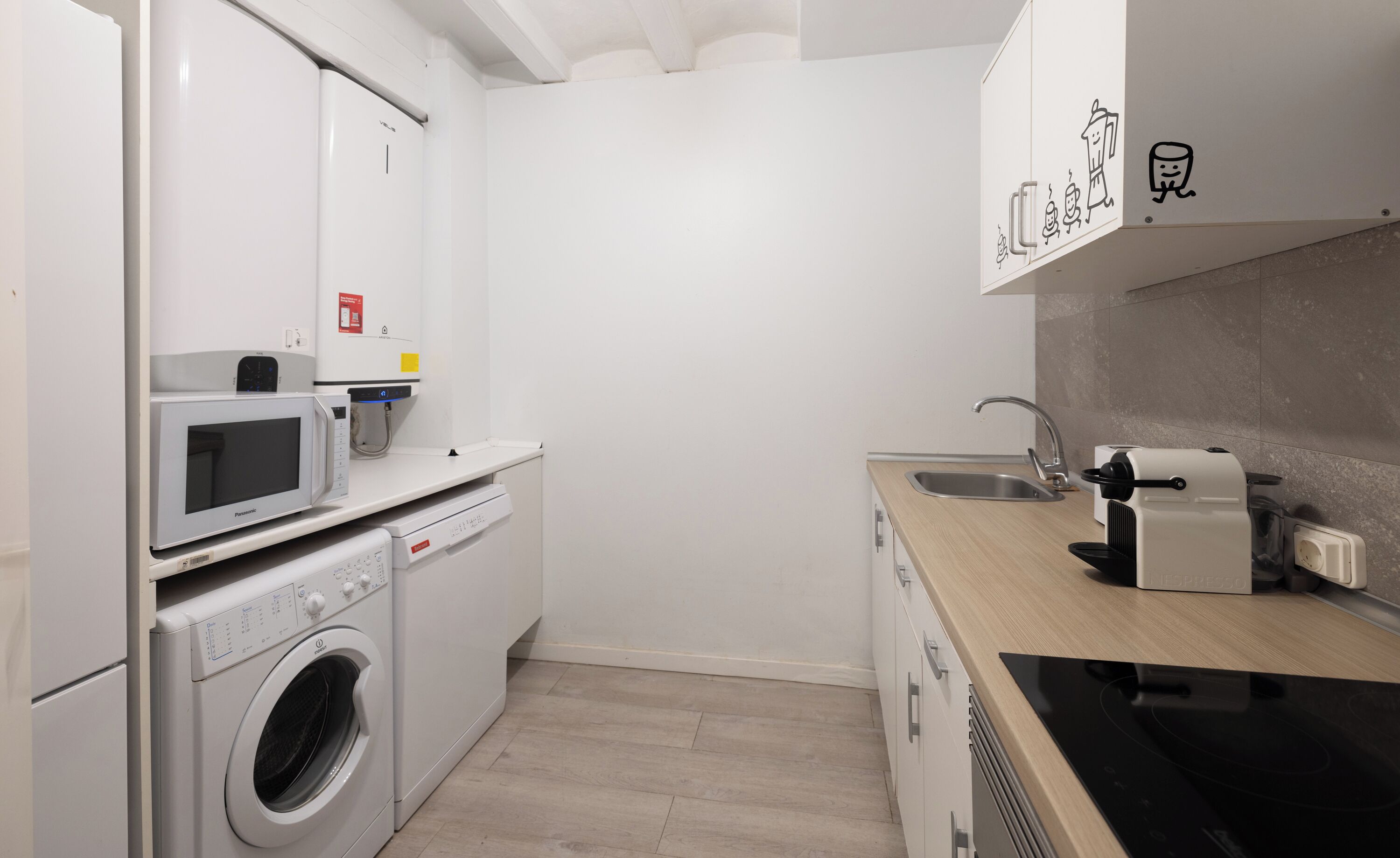 Una cocina compacta con lavadora, microondas, máquina de espresso y un lavabo.