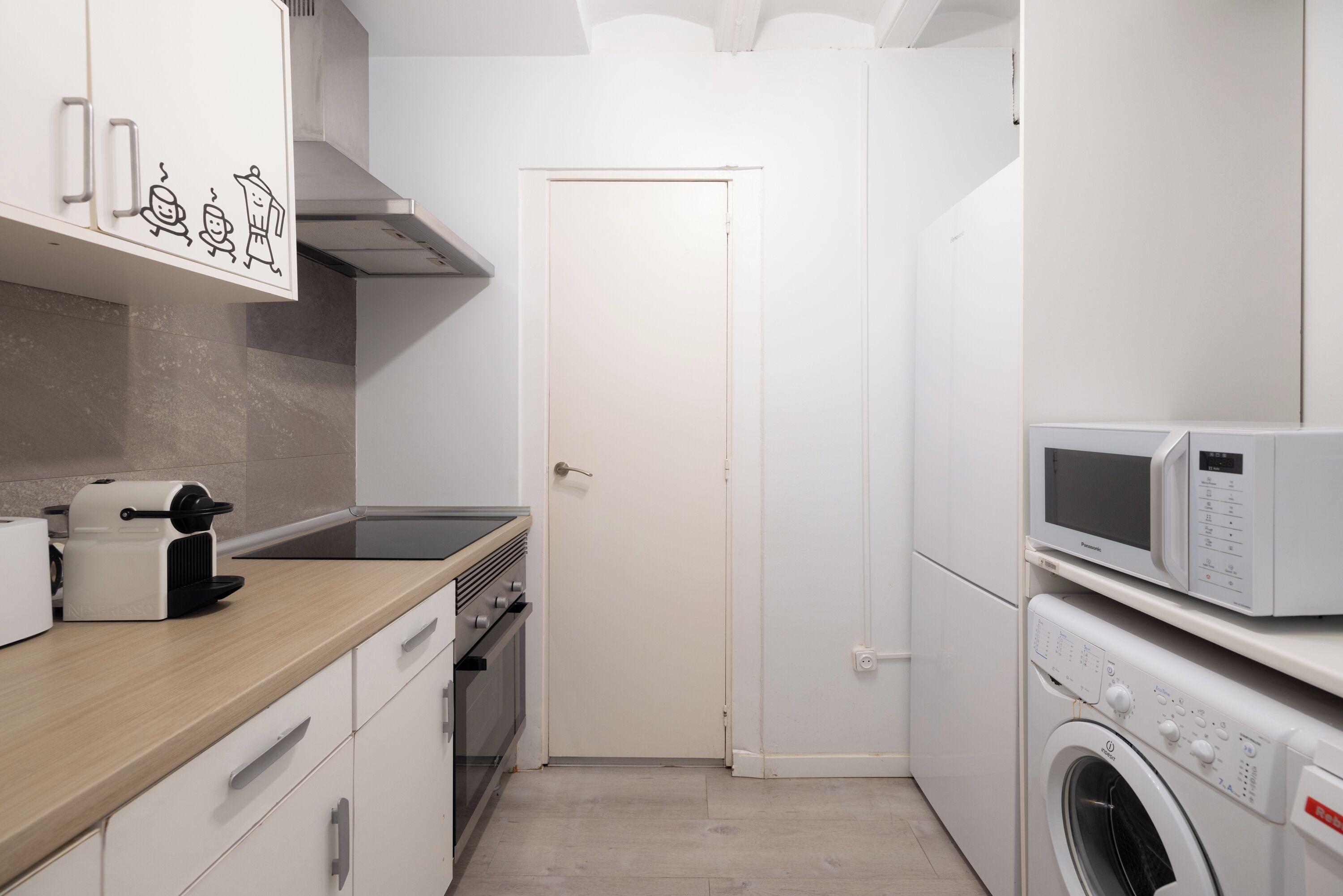 Una cocina compacta con microondas, horno y lavadora.