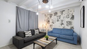 A modern living room with a grey sectional sofa, a blue sofa, and a wooden coffee table with a plant.