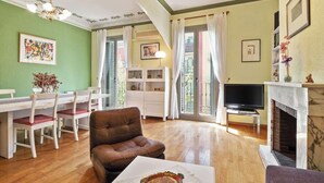 Una sala de estar con chimenea, televisor, comedor con mesa y sillas, y un sofá.