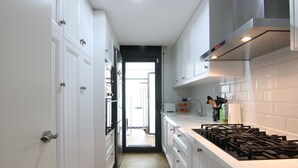 A modern kitchen with white cabinetry, a gas stove, and a view into the dining area. - Stay U-nique Villa Marinada (Calafell)