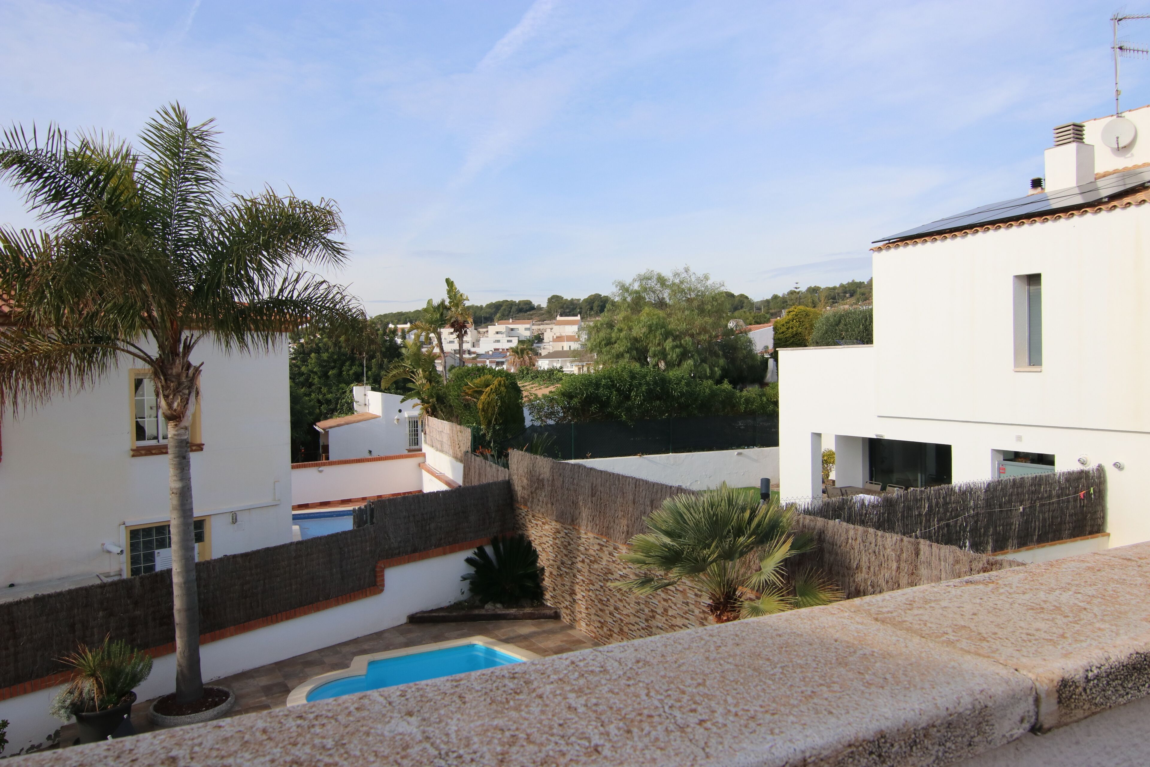 Zona residencial con edificios blancos, piscina y palmeras.