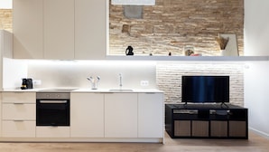Een moderne keuken met een inbouwoven, een spoelbak en een flatscreen televisie.