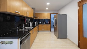 Une cuisine moderne avec des meubles en bois, un réfrigérateur en acier inoxydable et un plan de travail noir.