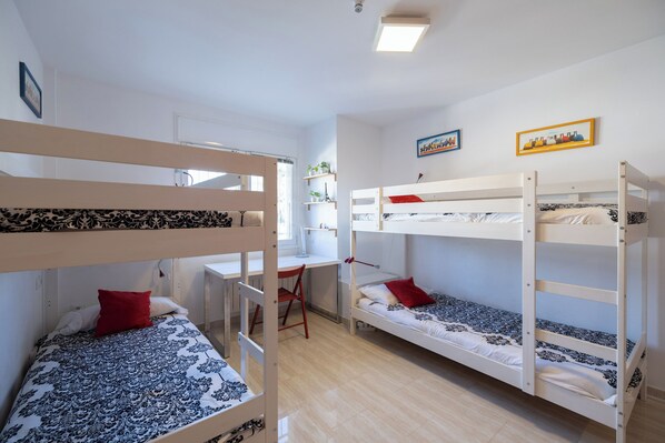Una habitación tipo dormitorio con literas, un escritorio y una silla.