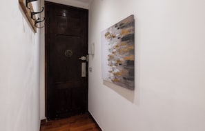 Un pasillo con una puerta de madera y un cuadro abstracto colgado en la pared.